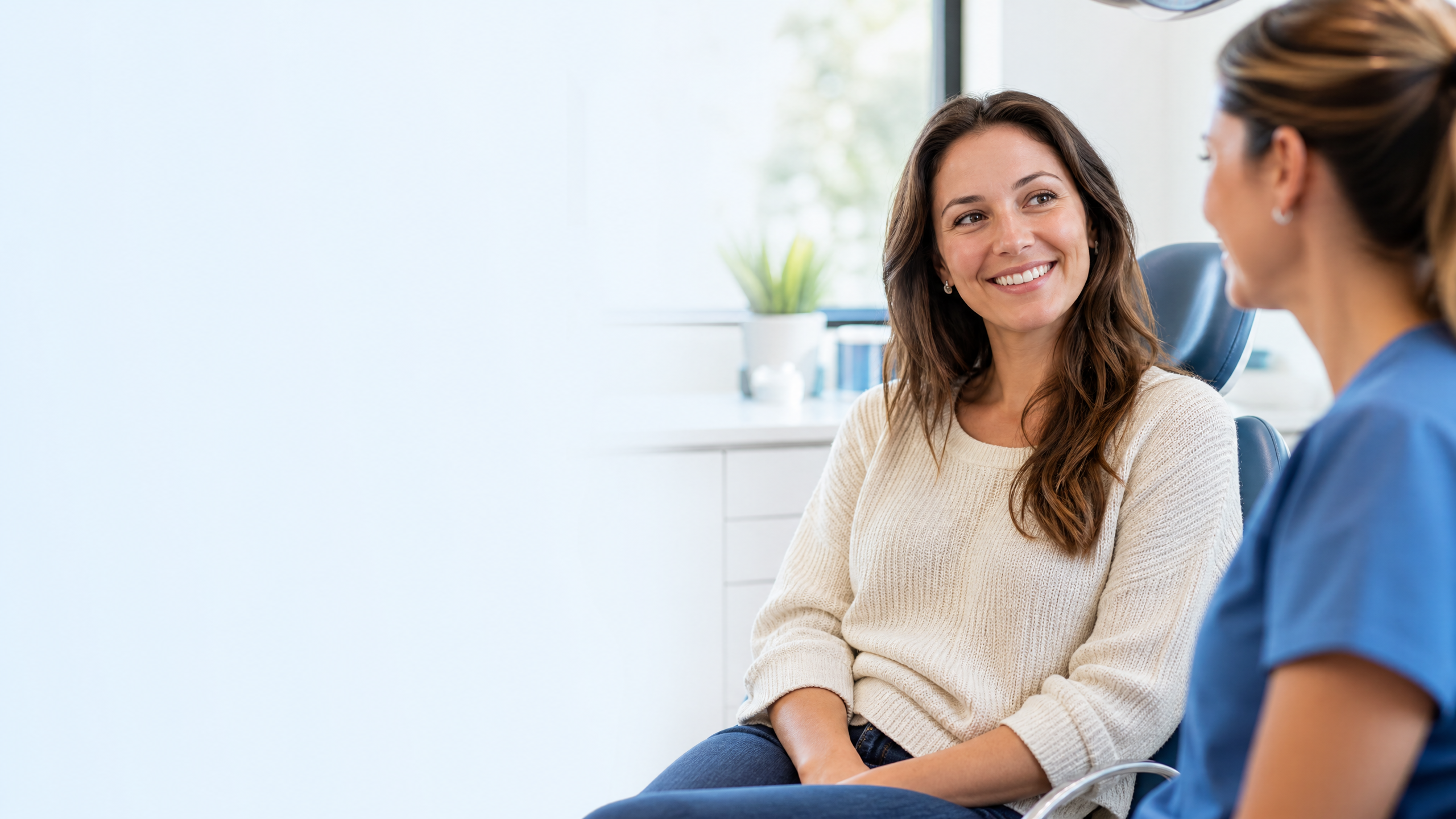 Adult patient smiling during a clear-aligner consultation in a bright dental office